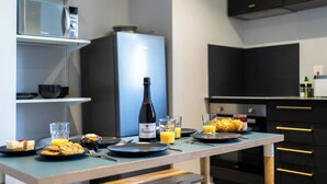 A modern kitchen with a dining table set for breakfast, including a bottle of wine, glasses, and pastries. - #158 Cozy Flat Near Bournemouth Beach - Sleeps 10 (Bournemouth)