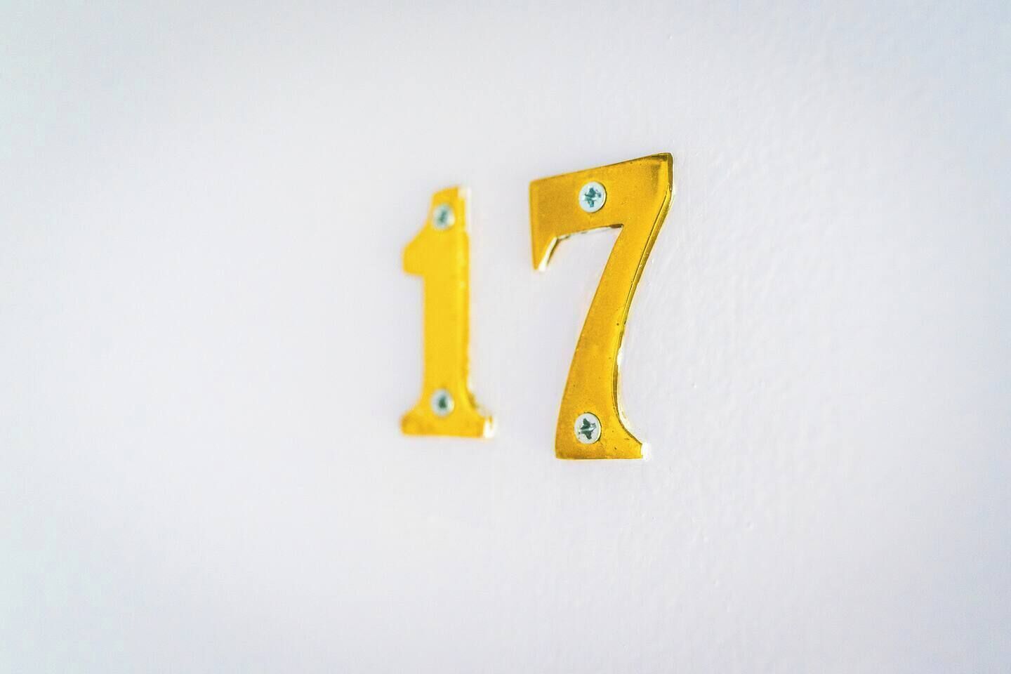 Two metallic numbers, 17, mounted on a white wall.