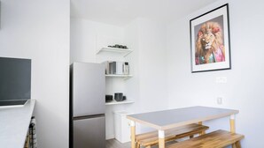 A compact kitchen with a refrigerator, microwave, and a small dining table with benches. - #158 Cozy Flat Near Bournemouth Beach - Sleeps 10 (Bournemouth)