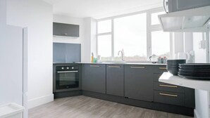 A modern kitchen with a built-in oven, grey cabinets, a window, and a white countertop. - #158 Cozy Flat Near Bournemouth Beach - Sleeps 10 (Bournemouth)