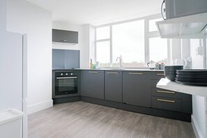 A modern kitchen with a built-in oven, grey cabinets, a window, and a white countertop. - #158 Cozy Flat Near Bournemouth Beach - Sleeps 10 (Bournemouth)