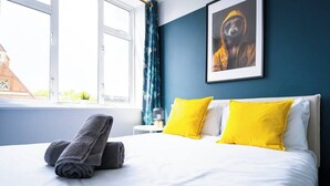 Hotelkamer met een bed, twee kussens, een handdoek, een raam en een ingelijst kunstwerk aan de muur.