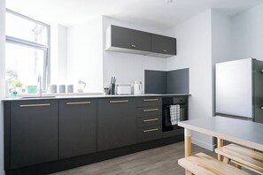 Eine moderne Küche mit dunklen Schränken, einem eingebauten Backofen und einem Fenster, das natürliches Licht hereinlässt.