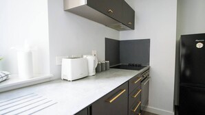 Eine moderne Küche mit weißer Arbeitsplatte, schwarzen Schränken und einem schwarzen Kühlschrank.