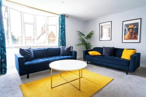 A living room with two sofas, a round coffee table, and a yellow rug. - #156 Coastal Stay Bournemouth - Sleeps 10 (Bournemouth)