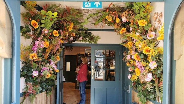 Ein Durchgang mit einem floralen Bogen, der zu einem Raum mit Fenster und Tür führt.