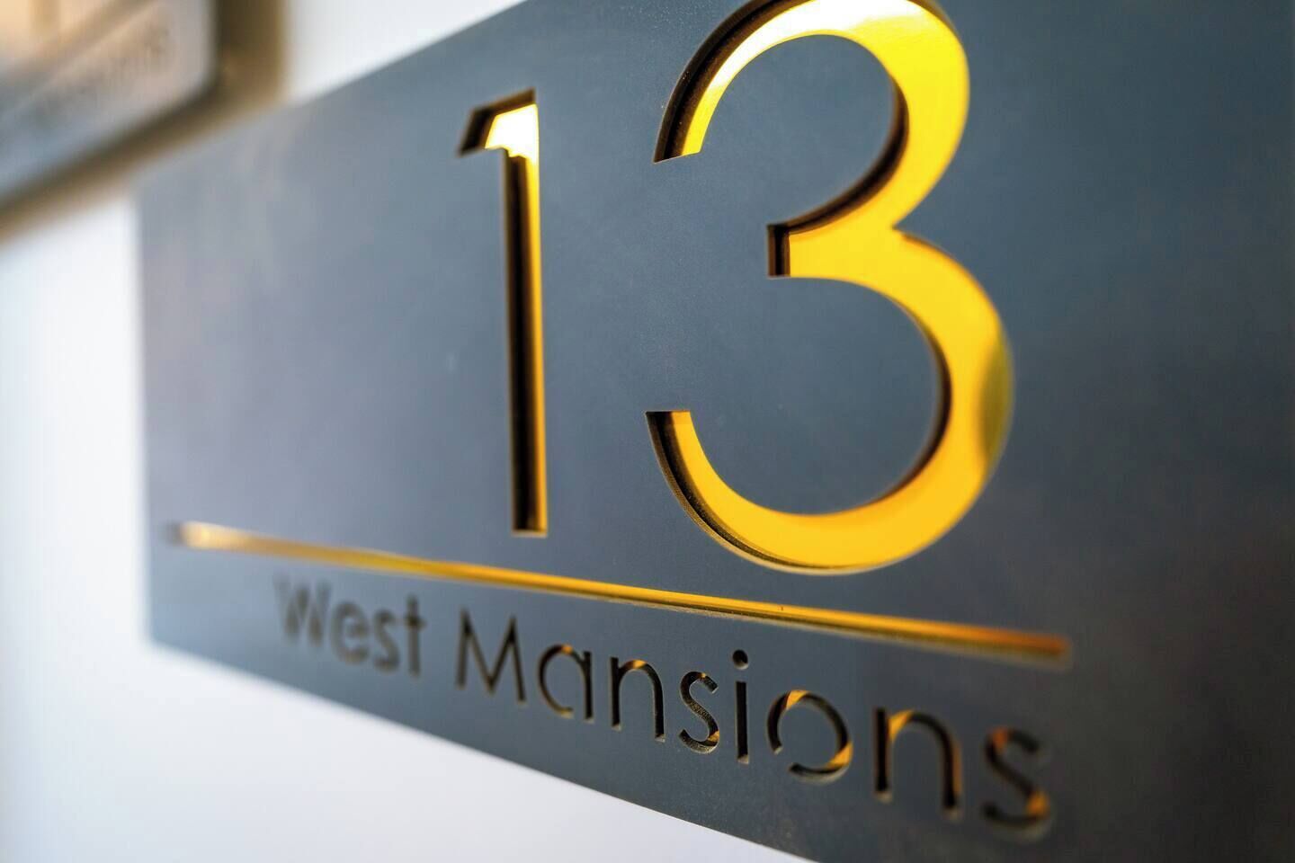 Eine Nahaufnahme eines Schildes mit der Nummer 13 und dem Text 'West Mansions'.