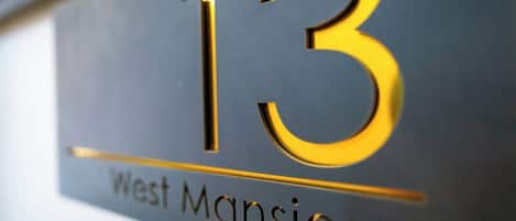 A close-up of a sign with the number '13' and the text 'West Mansions.'