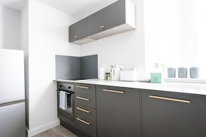 Uma cozinha moderna com armários escuros, bancada branca e janela com luz natural.