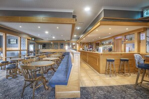 Un restaurante con barra, disposición de mesas y suelo estampado.