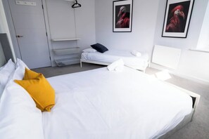 A hotel room with a large bed, a bedside table, a wardrobe, and two framed pictures on the wall. - #150 Bright Apt – Westbourne Area - Sleeps 7 (Bournemouth)