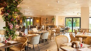 A restaurant with wicker furniture, large windows, and a view of greenery outside. - #150 Bright Apt – Westbourne Area - Sleeps 7 (Bournemouth)