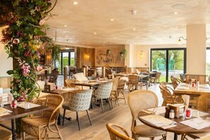 A restaurant with wicker furniture, large windows, and a view of greenery outside. - #150 Bright Apt – Westbourne Area - Sleeps 7 (Bournemouth)