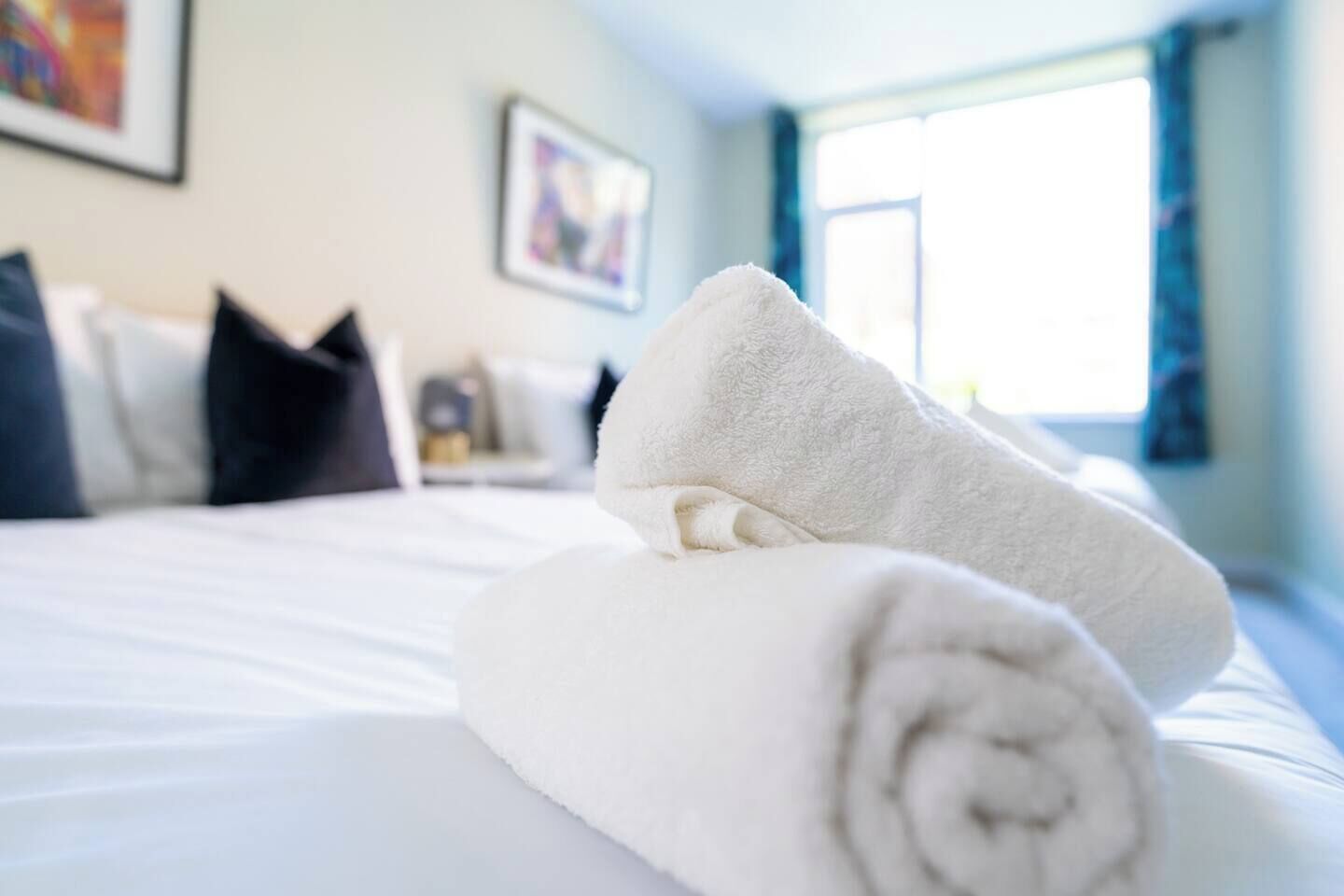 Un lit bien fait, avec du linge de lit blanc et des serviettes blanches pliées.