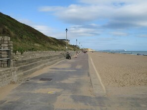 Eine Küstenstraße mit einer Steinmauer auf der einen Seite und einem Sandstrand auf der anderen.