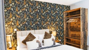 A bedroom with a patterned wallpaper, a wooden wardrobe, and a bed with white bedding and leopard print pillows. - #146 Urban Stay at Sapphire Court - Sleeps 6 (West Midlands)