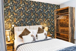 A bedroom with a patterned wallpaper, a wooden wardrobe, and a bed with white bedding and leopard print pillows. - #146 Urban Stay at Sapphire Court - Sleeps 6 (West Midlands)