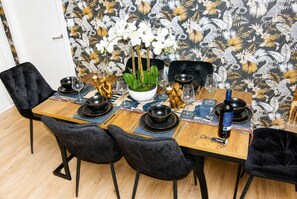 A dining table set with black and gold dinnerware, a bottle of wine, and a potted plant. - #146 Urban Stay at Sapphire Court - Sleeps 6 (West Midlands)