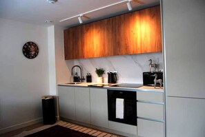 Una cocina moderna con armarios de madera, encimera negra y lavavajillas integrado.