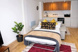 Een kleine slaapkamer met een bed, nachtkastje en een potplant.