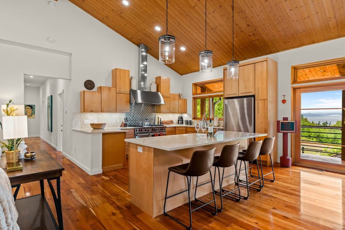A modern kitchen with wooden cabinets, stainless steel appliances, and a large island with bar stools.