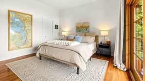 A bedroom with a large bed, a map on the wall, and a window with curtains. - The Residence at Freshwater Bay (Port Angeles)