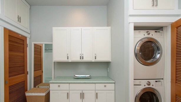 A laundry room with white cabinets, a washing machine, and a drying machine. - The Residence at Freshwater Bay (Port Angeles)