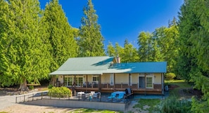 A two-story lodge with a covered deck and outdoor seating area. - The Residence at Freshwater Bay (Port Angeles)