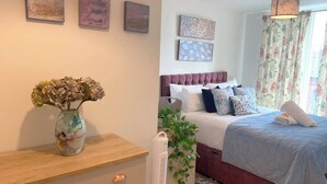 A bedroom with a bed, bedside table, and a vase with flowers. - #164 Coral retreat in Birmingham CC -Sleeps 6 (West Midlands)