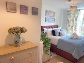 A bedroom with a bed, bedside table, and a vase with flowers. - #164 Coral retreat in Birmingham CC -Sleeps 6 (West Midlands)