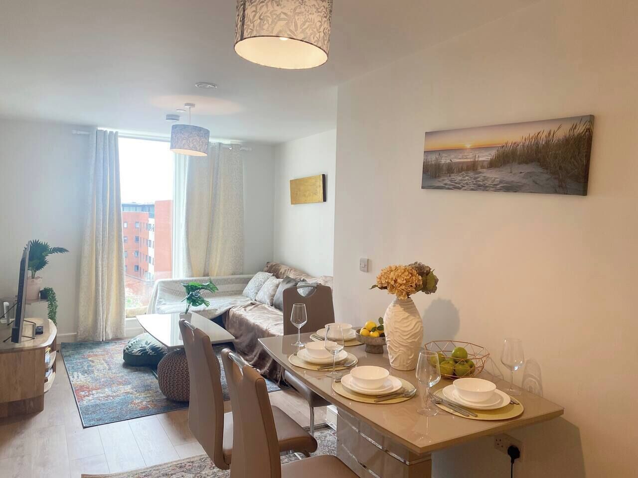 A modern living room with a dining area, a sofa, a TV, and a painting on the wall.