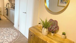 A hallway with a wooden console table, a round mirror, and a potted plant. - #164 Coral retreat in Birmingham CC -Sleeps 6 (West Midlands)