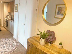 A hallway with a wooden console table, a round mirror, and a potted plant. - #164 Coral retreat in Birmingham CC -Sleeps 6 (West Midlands)