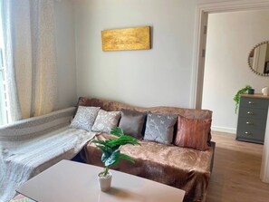 Ett vardagsrum med en soffa, ett soffbord och en växt.