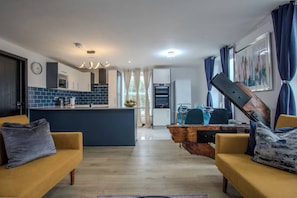 Una cocina moderna con una isla central, un comedor con una mesa de madera y una sala de estar con dos sofás.