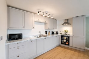 Una cocina moderna con armarios blancos, microondas integrado, lavamanos y estufa.