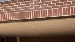 A parking area with marked spaces, a brick wall, and a door.