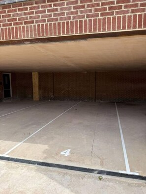 A parking area with marked spaces, a brick wall, and a door.