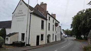 A white building with a sign for 'The Three Horseshoes' which is a country inn offering dining, handmade chocolates, fine foods, and a gift shop.