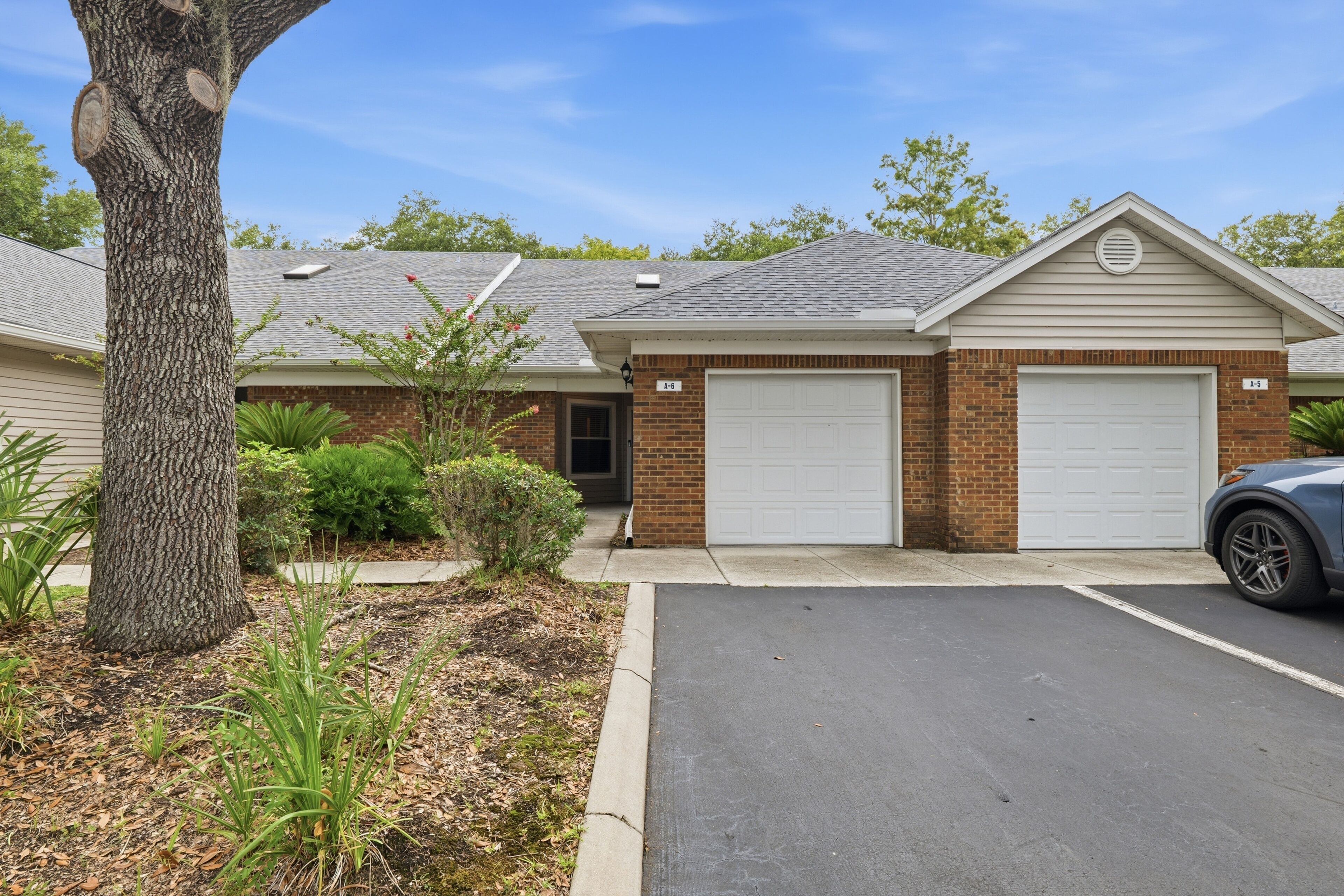 A residential property with a brick garage, a single-story house, and a driveway.