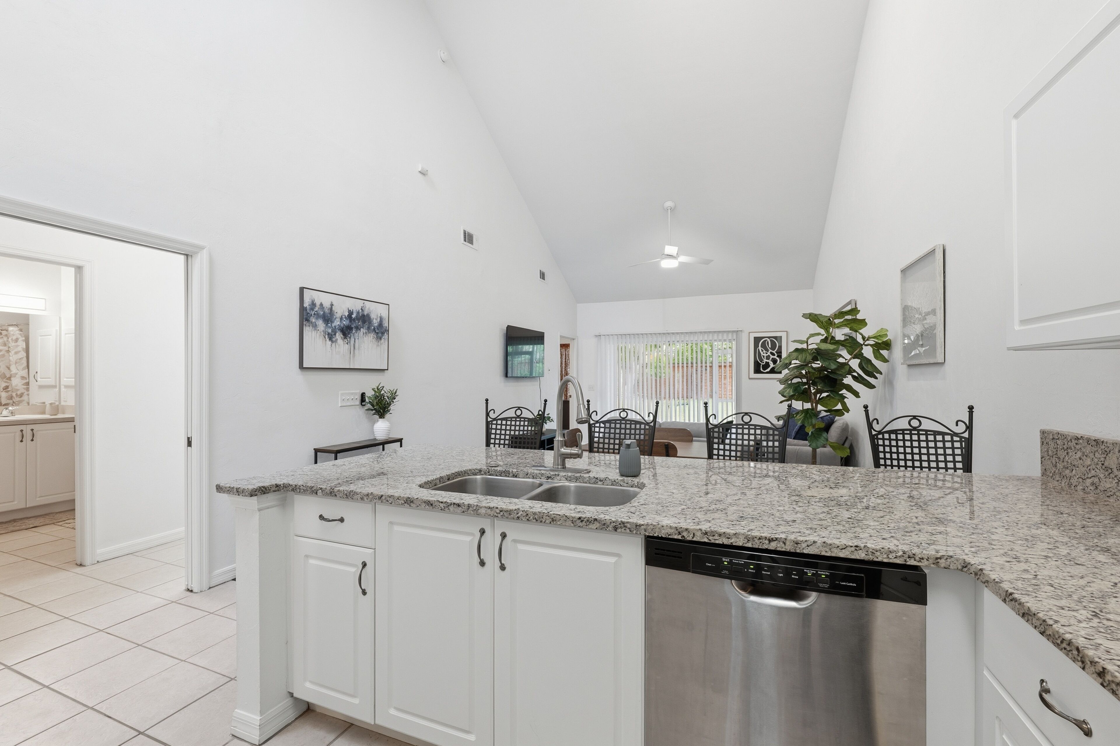 A modern kitchen with white cabinetry, granite countertops, and a stainless steel dishwasher.