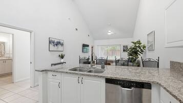 A modern kitchen with white cabinetry, granite countertops, and a stainless steel dishwasher.