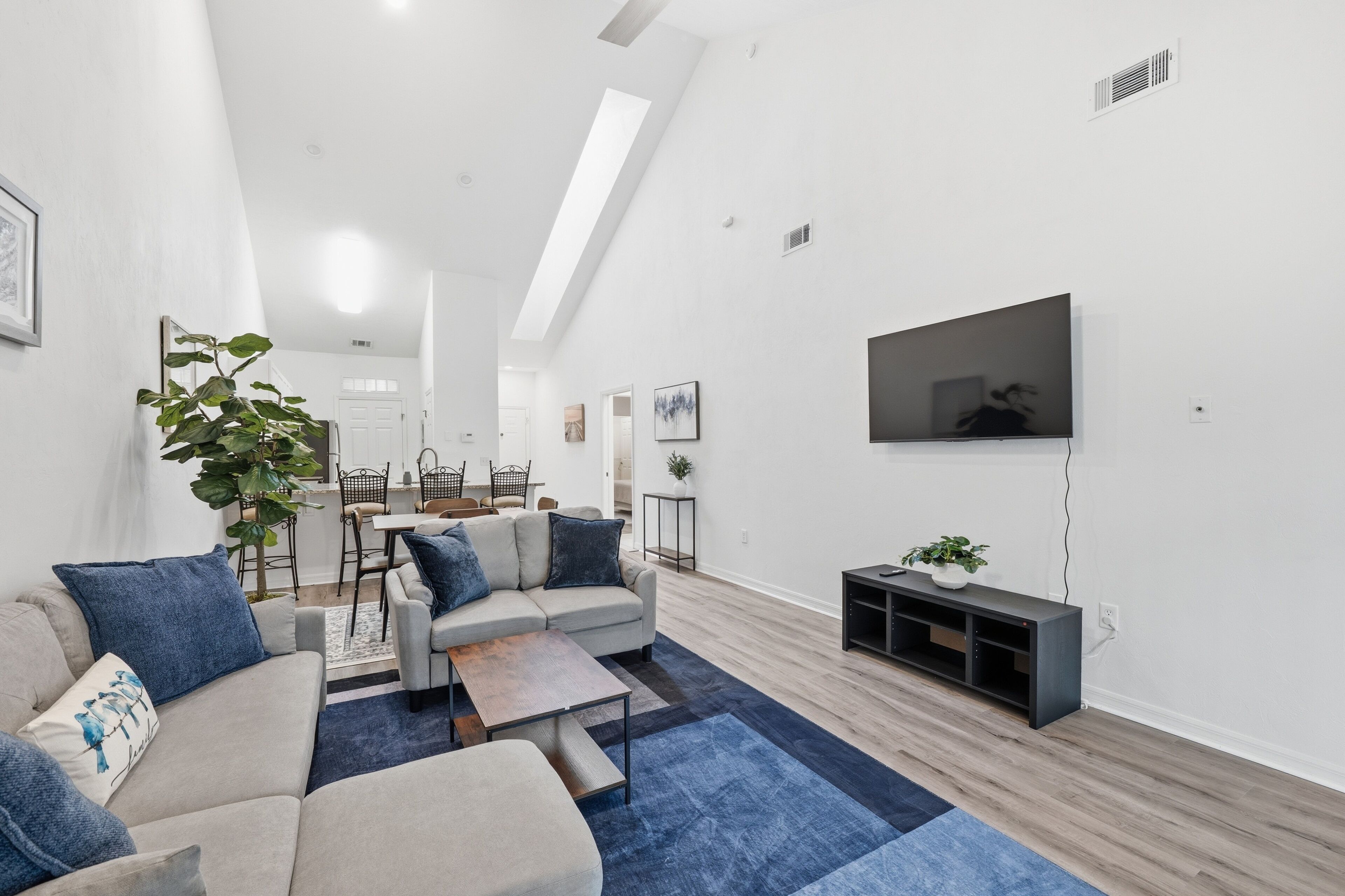A modern living room with a sofa set, coffee table, and a flat-screen TV mounted on the wall.