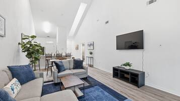 A modern living room with a sofa set, coffee table, and a flat-screen TV mounted on the wall.