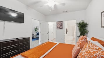 A bedroom with a bed, a dresser, a television, and a ceiling fan.