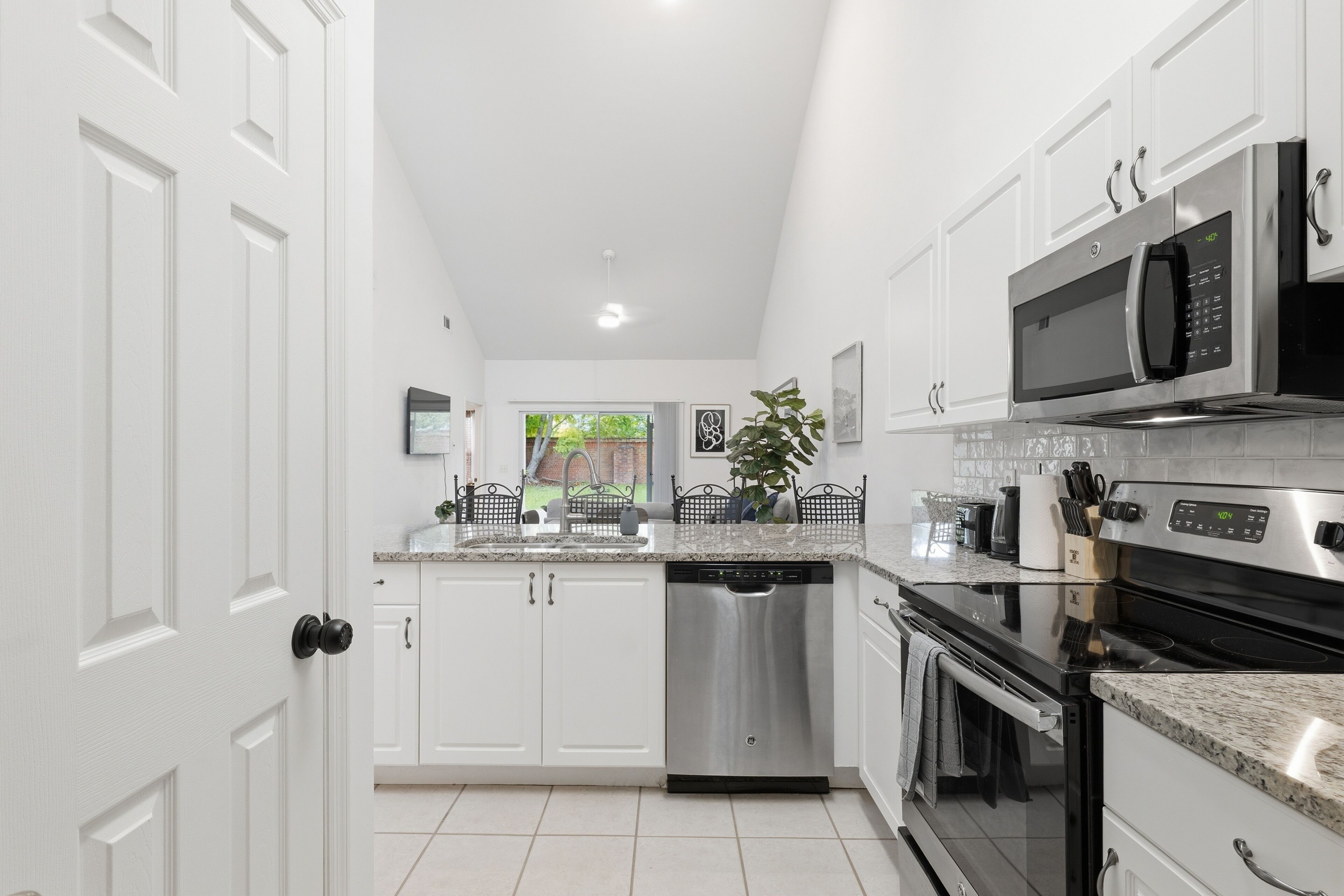 A modern kitchen with white cabinetry, stainless steel appliances, and a central island.