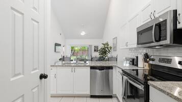 A modern kitchen with white cabinetry, stainless steel appliances, and a central island.