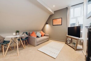 A modern living room with a sofa, a coffee table, a TV stand, and a large window. - #44 Victoria Apartment3|near snowdome| Guest for 4 (Staffordshire)