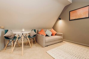 Ein gemütliches Zimmer mit Esstisch, Stühlen, einer Couch und einem Teppich.