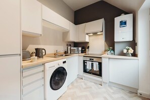 A modern kitchen with a washing machine, oven, microwave, and a built-in dishwasher.